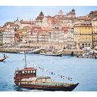 "CRUZEIROS DOURO" auf Schiff; Altstadtansicht: Fluss, Boote, bunte Häuser am Hang, malerische Architektur.