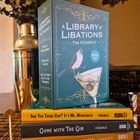 Texte: "A Library of Libations," "Tequila Mockingbird," "Gone with the Gin," "Are You There God? It’s Me, Margarita." Bücherstapel auf Tisch.