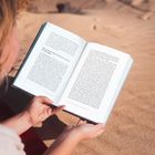 Offenes Buch mit Titel "Wenn Nerven durch Schmerzen nerven – die Neuralgie", gehalten von einer Person im sandigen Gelände.