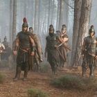Eine Gruppe antiker Soldaten in Rüstungen marschiert durch einen dichten, nebligen Wald.