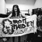 Eine Person hält ein Banner mit „IRON MAIDEN“ und „OVER THE TOP“, daneben eine gezeichnete gruselige Figur.