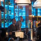 Zapfhähne mit den Logos von "Kona Brewing Co.", "Coors" und "Blue Moon". Zwei lächelnde Personen an der Bar.