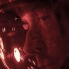 Ein Gesicht, durch einen Helm geschützt, beleuchtet von warmem, rotem Licht.