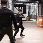 Texte: "Dangerous". Zwei Männer im Kampfpose in einem industriellen Gang. Hintergrund enthält Fässer und Ausrüstung.