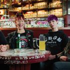 Ein Tisch mit Graffiti darauf. Vier lachende Frauen in einem gemütlichen, dekorierten Raum mit leeren Gläsern im Hintergrund.