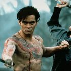 Zwei Personen. Der Mann mit Drachen-Tattoos hält ein Schwert, die Frau schreit mit erhobenem Schwert. Dramatisch und intensiv.