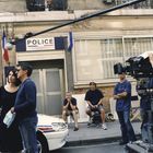 POLICE-Schild. Filmteam bei Dreharbeiten vor einer Polizeistation. Drei Menschen im Gespräch, Kamera und Ton-Angel dabei.