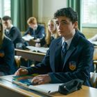 Mehrere Schülerinnen und Schüler in Schuluniformen sitzen aufmerksam in einem Klassenzimmer an ihren Tischen.