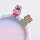 Eine rosa Häschenfigur mit rotem Herz und eine Bärenfigur mit grünem Kleeblatt an einem pastellfarbenen Teller.