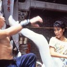 Zwei kämpfende Personen in martialischer Pose, Hintergrund traditionelles asiatisches Gebäude. Dynamische Szene.