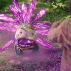 Ein kleines, farbenfrohes Wesen mit leuchtenden, violetten "Blütenblättern" steht einem Kind in einer Waldszene gegenüber.