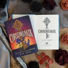 „CURSEBREAKER“ von R. M. Gray, zeigt ein kunstvolles Schlüsseldesign. Umgeben von dunklen Rosen und Stoff.