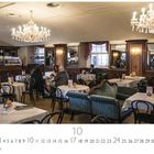 Café Schönbrunn. Kalenderblatt für den Monat Oktober. Menschen sitzen an runden Tischen in einem eleganten Kaffeehaus.