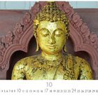 Zahlen 1-31 unten, mit "10" hervorgehoben. Eine Statue eines goldenen Buddhas vor einem dekorativen, roten Hintergrund.