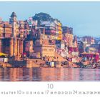 "Varanasi" und "10" unten. Lebendige Gebäude am Wasser, bunte Boote, Menschen, historische Architektur.