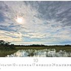 Text: "Everglades." Kalenderseite mit Datumsanzeige. Sumpflandschaft unter bewölktem Himmel mit Sonne.