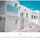 "ANIMA MYKONOS" in bläulichen Buchstaben auf einem Schild. Weiße Gebäude und blauer Himmel in der typischen Architektur von Mykonos.
