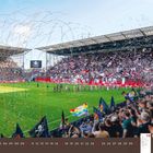 Oktober 2027 Kalenderseite; Fußballstadion voller Fans, bunte Flaggen und Konfetti, Spieler betreten das Spielfeld.
