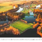 Kalenderseite für Oktober, Landschaft mit Feldern, Teichen und Gebäuden in warmem Licht.