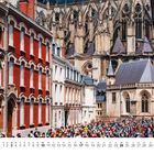 Monatskalender zeigt Oktober; Hintergrund: gotische Kathedrale, rote Ziegelhäuser, Menschenmenge in bunten Outfits.