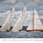 Zahlen und Buchstaben auf Segeln: K 12, US 15, N 15. Drei Segelboote auf See, im Hintergrund bewölkter Himmel.