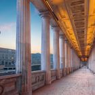 Säulengang mit Blick auf Fernsehturm und Gebäude in der Dämmerung; kunstvoll erleuchtete Decke und Flussansicht.