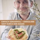 EINFACH GENUSSVOLL – (DEKO)LIEBE GEHT DURCH DEN MAGEN. Ein Mann hält ein Gebäck mit Schinken und Spargel.