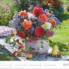 OKTOBER. Ein bunter Blumenstrauß auf einem Holztisch im Garten, daneben Obst: Apfel, Birne, Hagebutten.