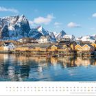 Text "Oktober" und Kalendarium unten. Küste mit gelben Häusern, dahinter schneebedeckte Berge, klarer Himmel.