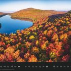 Kalender für Oktober mit markierten Datumsangaben. Herbstlandschaft mit buntem Wald um einen See, Hügel im Hintergrund.