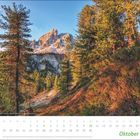 Oktoberkalender: Oktoberdaten mit Feiertagen. Bild zeigt Berglandschaft mit Bäumen im warmen Sonnenlicht.