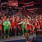 Text: "OKTOBER", Monatskalender. Fußballspieler in roten Trikots feiern; ein Pokal steht im Vordergrund.