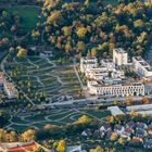 Ein modernes Stadtviertel mit weißen Gebäuden, weitläufigen Grünflächen und geschwungenen Wegen, umgeben von Bäumen.