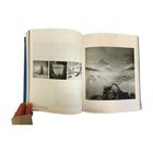 Offene Buchseiten mit Schwarz-Weiß-Fotos von Berglandschaften und Bäumen. Links mehrere kleinere Fotos, rechts ein großes.