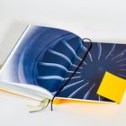 Ein Buch mit einem Bild einer Turbine aufgeschlagen; ein gelber Zettel ragt aus der rechten Seite.