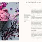 Holunder-Sorbet: Ein schwarzes Waffelhörnchen mit pinkem Eis, umgeben von lila und rosa Blüten sowie Holunderbeeren.
