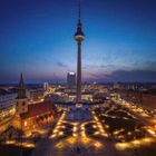 Keine Texte sichtbar. Ein Nachtpanorama mit einem hohen Turm, beleuchteten Straßen und Gebäuden, darunter eine Kirche.