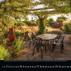 10, Oktober 2023; Kalender. Garten mit Tisch, sechs Stühlen, üppigem Grün, überdacht von Blätterdach, warmes Sonnenlicht.