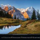 10, 2023, 1 bis 31; Berge im Hintergrund, grüne Wiese und ein kleiner See vorne, umgeben von Bäumen.