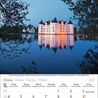 Ein Kalender für Oktober 2027. Ein beleuchtetes Schloss spiegelt sich im Wasser, umrahmt von Bäumen bei Abenddämmerung.