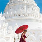 Kalenderseite "10 2021" unten. Junge in rotem Gewand hält roten Schirm vor weißem Tempel mit blauem Himmel.