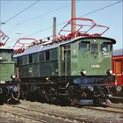 Alter Lokomotivmodell, grün mit rotem Stromabnehmer, Text: "E44 508", steht auf Schienen, umgeben von anderen Zügen.