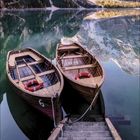 Kalenderblatt mit „10 2021“ und Daten darunter; ein Holzsteg, zwei Boote auf einem ruhigen, von Bergen umgebenen See.