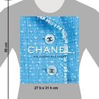 Text: "CHANEL: DIE ESSENZ DES LUXUS". Großaufnahme eines blauen Stoffs mit Knöpfen, auf einem grauen Shirt platziert.