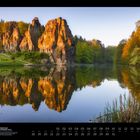 "Die Externsteine im Teutoburger Wald" steht unten. Majestätische Felsen spiegeln sich im Wasser, umgeben von Wald.