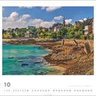 "Dinard | Foto © Pochat Vivien." Eine Küstenlandschaft mit türkisfarbenem Wasser und Gebäuden auf einem Hügel am Ufer.