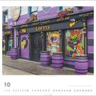 "Loftys Bar", "Live Music", "Raising the Bar". Bunt bemalte Fenster, lila und schwarze Fässer vor einer farbenfrohen Fassade.