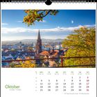 Oktoberkalender mit Stadtansicht, herbstliche Bäume, Kirchturm im Zentrum, blauer Himmel. Feiertage am 3. und 31. Oktober.