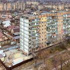 Ukrainska 55, after rehabilitation works (März 2020). Hochhaus mit Balkonen und Wohngebiet im Hintergrund, Bäume und Straße.