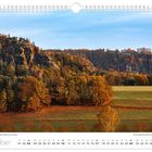 Der Kalender zeigt Oktober unter einer herbstlichen Landschaft mit Bäumen, Felsen und blauem Himmel.